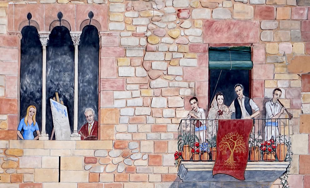Pintura mural executada per Carles Arola amb diversos personatges en una façana.