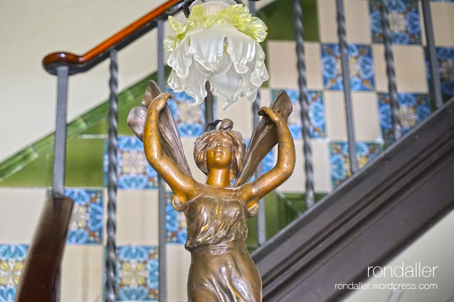 Figura femenina sostenint un llum modernista al vestíbul de la Casa Aguilar de Centelles (Osona)