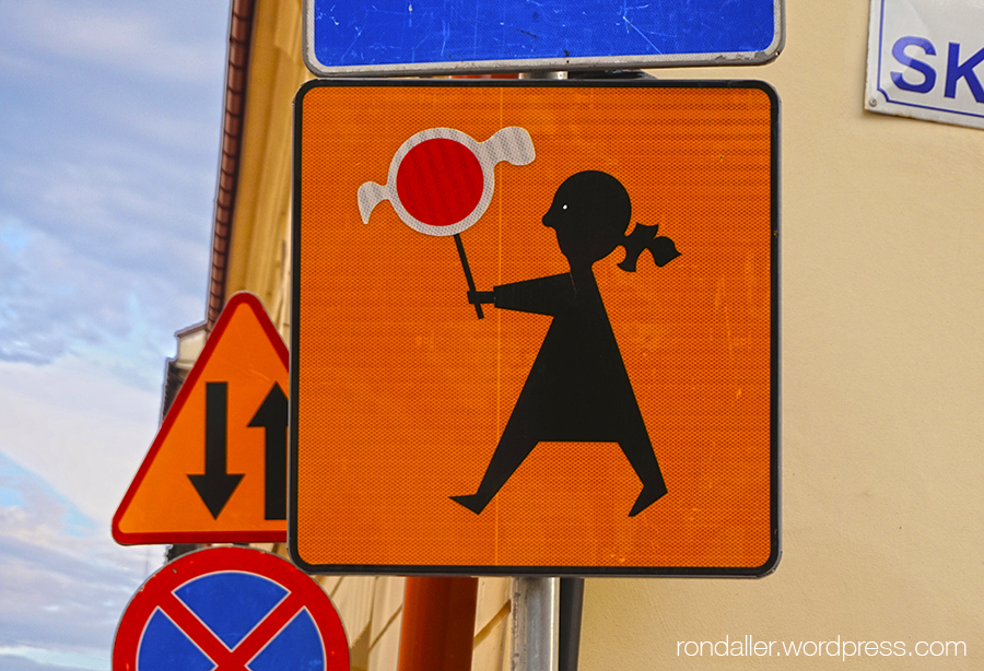 Diversos senyals de trànsit. En un es veu una nena caminant amb un senyal rodó a les mans.