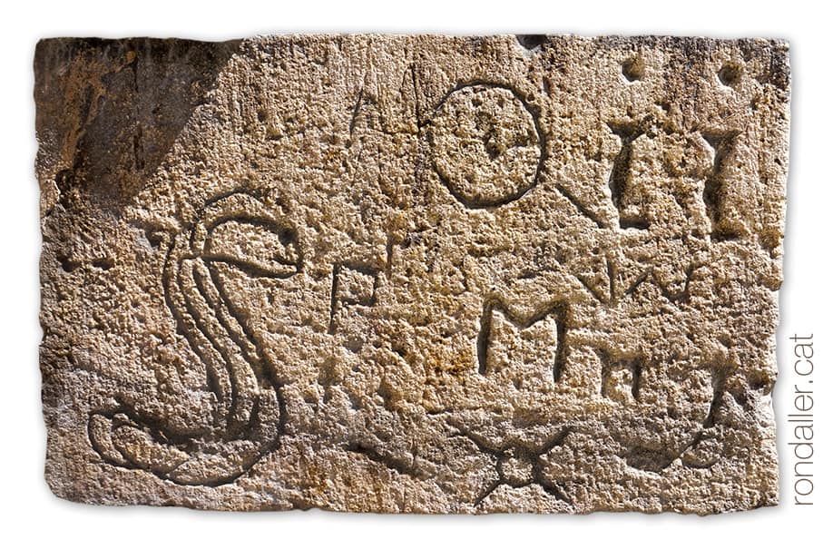 Un carreu del mur exterior amb diverses inscripcions, com una serp, lletres i altres simbols.