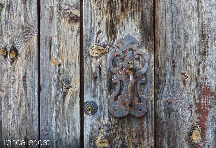 Picaporta de forja en una deslluïda porta de fusta d'aquesta poblacióde l'alta Cerdanya.