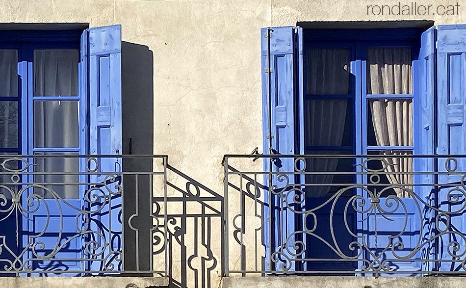 Dos balcons de forja amb les portes blaves al barri antic de La Tor de Querol a l'Alta Cerdanya.