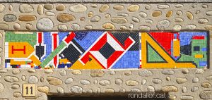Mosaic de tesel·les amb les eines de paleta a la llinda d’un edifici de L’Esquirol a Osona.
