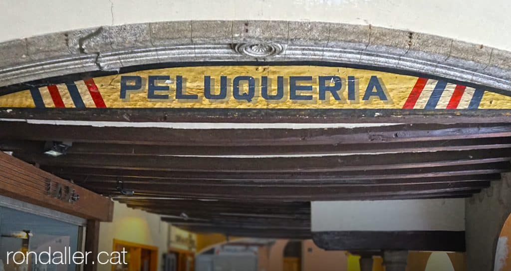 Rètol d'una perruqueria sota les porxades del carrer Major de la Seu d'Urgell.