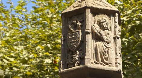 Detall dels relleus del tambor de la creu de terme de Tremp, obra gòtica del segle XVII, amb un escut i una figura.