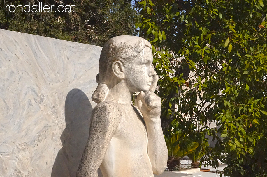 Escultura funerària d'una nena amb el dit a la boca en senyal de silenci.