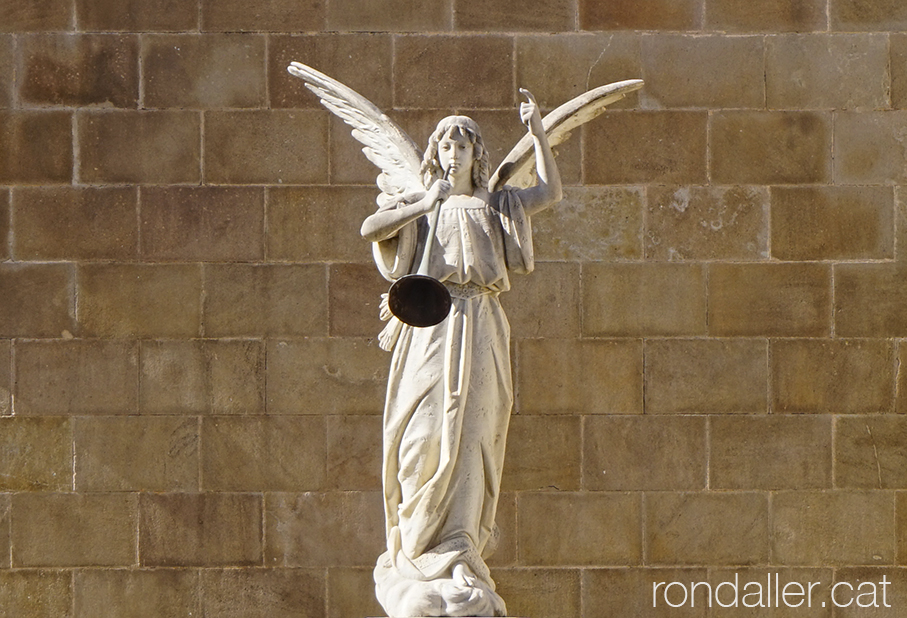 Sant Genís dels Agudells. Escultura d'un àngel tocant la trompeta al cementiri.