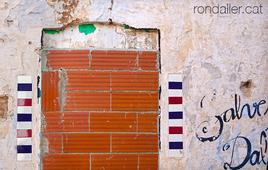 Porta tapiada d'una antiga barberia al carrer Lladó.