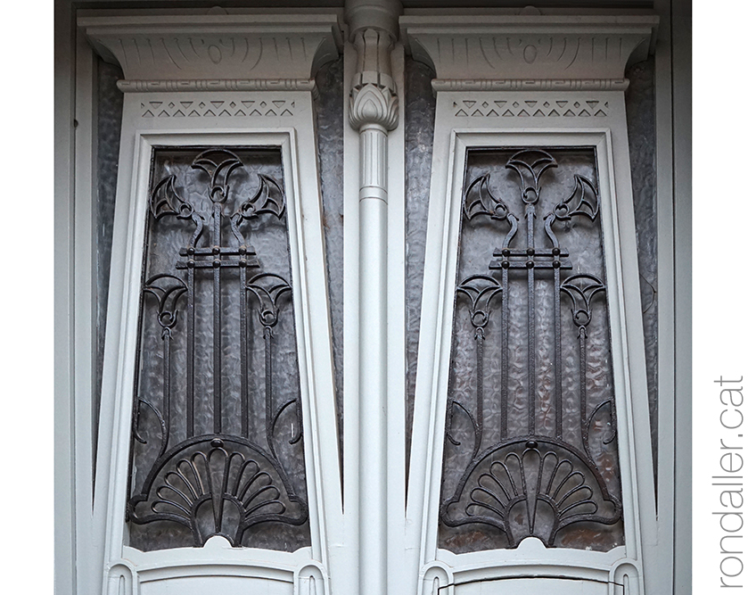 Detall de la porta de l'entrada principal de l'edifici amb reixes amb forma de flor.