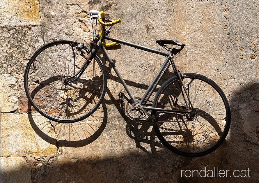 Nucli d'Orriols. Bicicleta antiga penjada en un mur al centre de la vila.