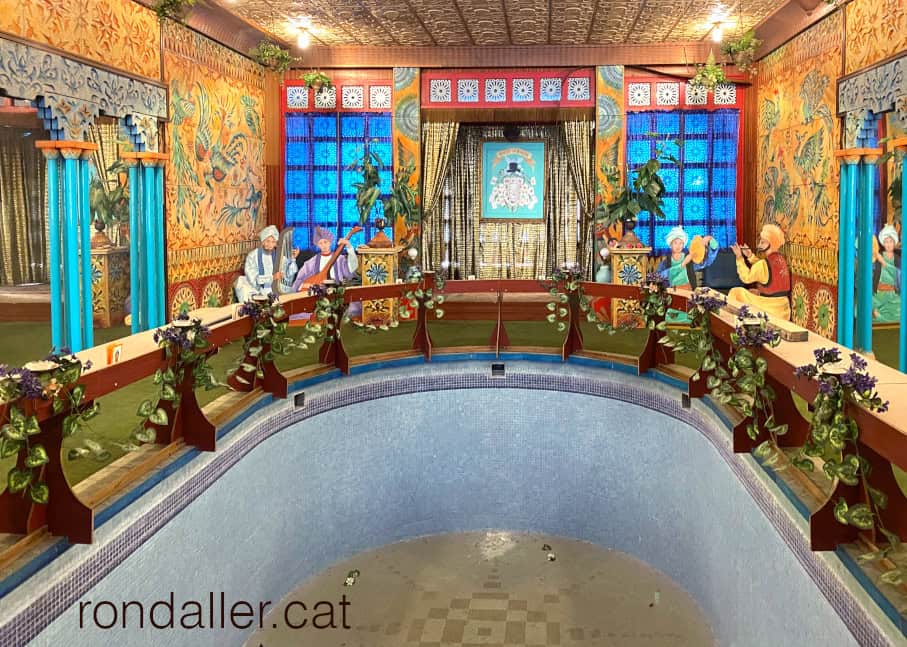 Gran sala amb una piscina, taules, miralls i un escenari.