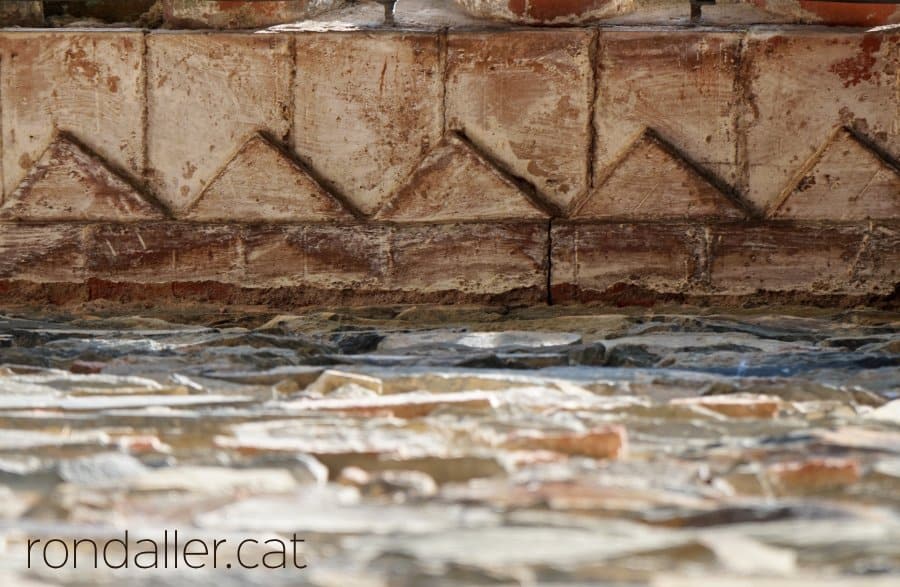 Detall del ràfec de l'església amb els maons disposats amb la forma de dents de llop.