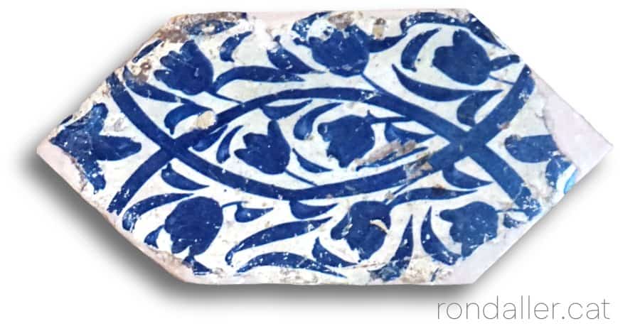 taulell hexagonal o alfardó del segle XV amb una decoració floral en color blau.