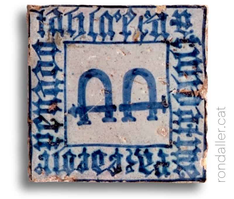 Rajoles del segle XV. Taulell amb unes manilles i una inscripció gòtica.