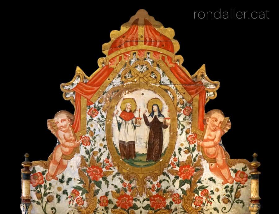 Capçal de llit d'Olot amb la representació d'una parella de sants, àngels i motius florals.