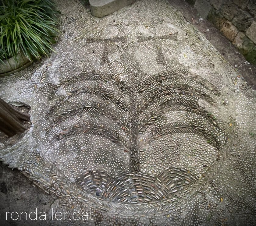 Escut de Tamarit de Mar fet amb còdols al paviment del jardí.
