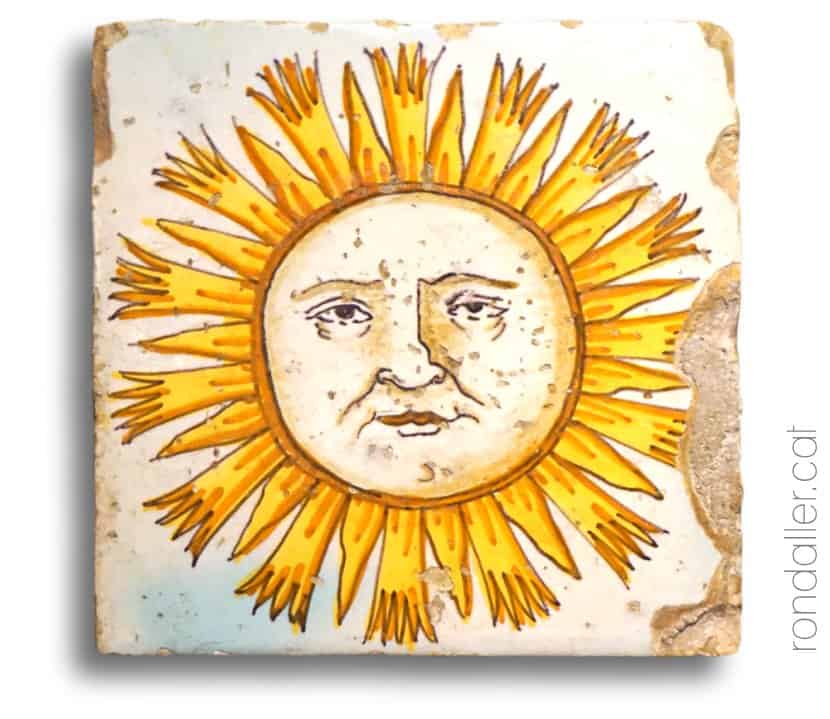 Taulella de la Fundació Mascort amb la imatge d'un sol amb cara i ulls.
