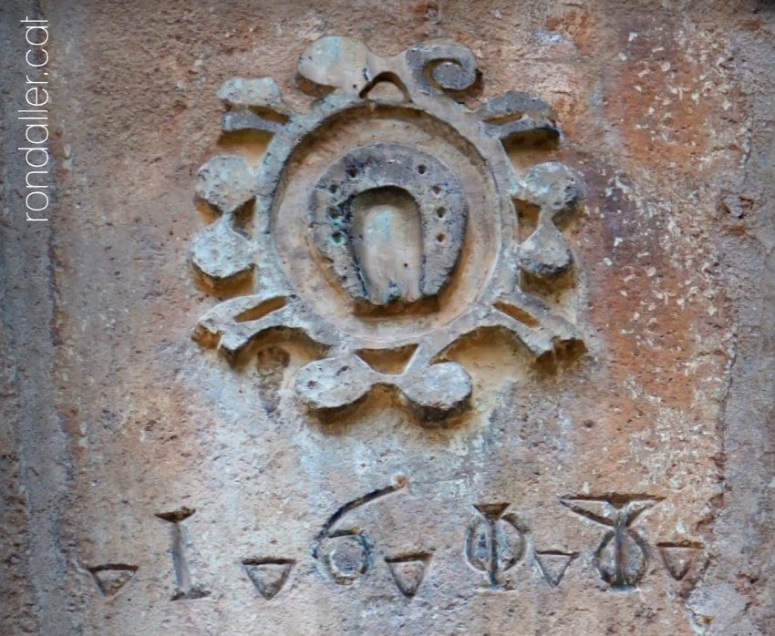 Llinda del segle XVII de Ca Caçador, amb la imatge d'una ferradura.